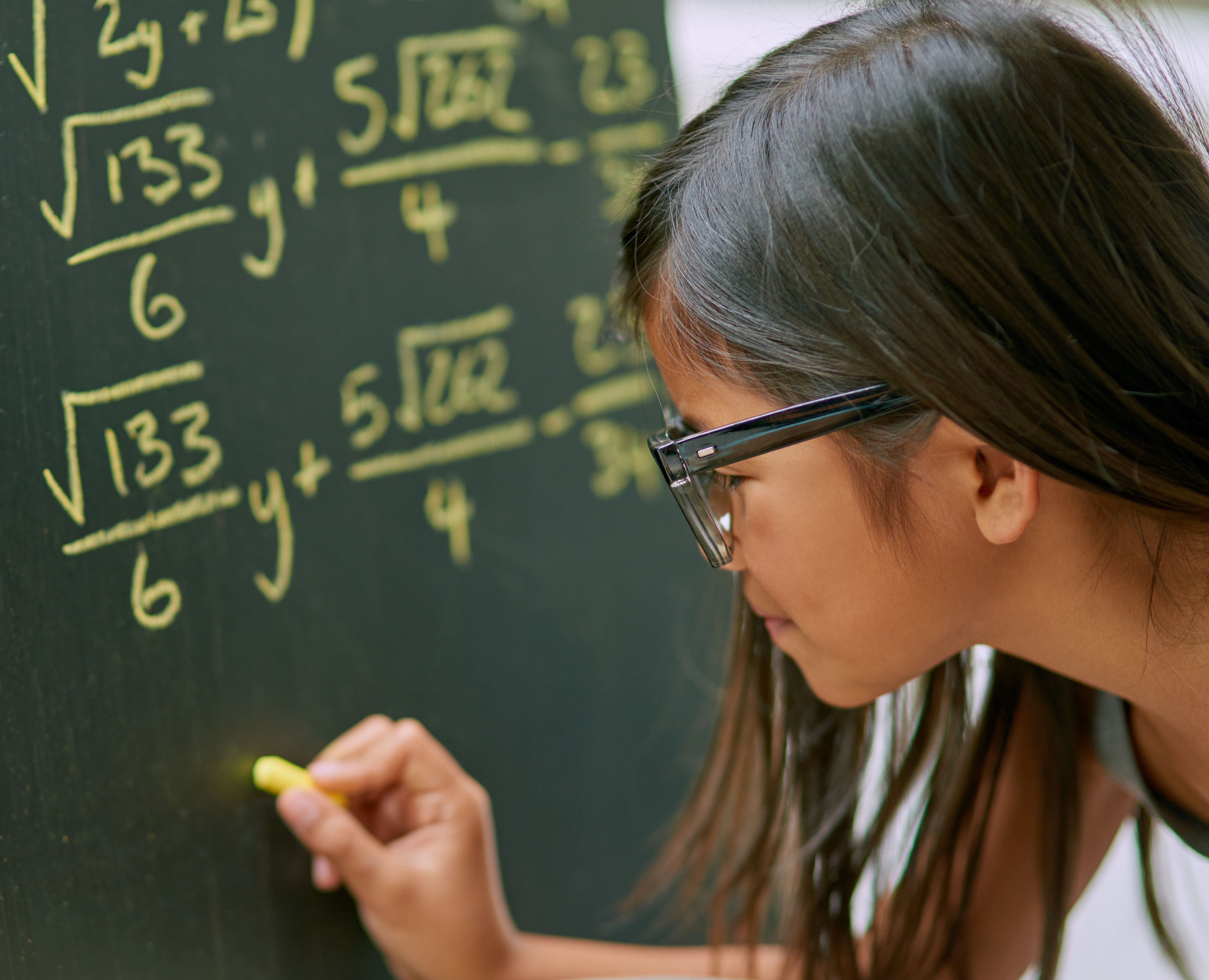 Student solving mathematical equations on a chalkboard during a math enrichment lesson focused on problem-solving skills.