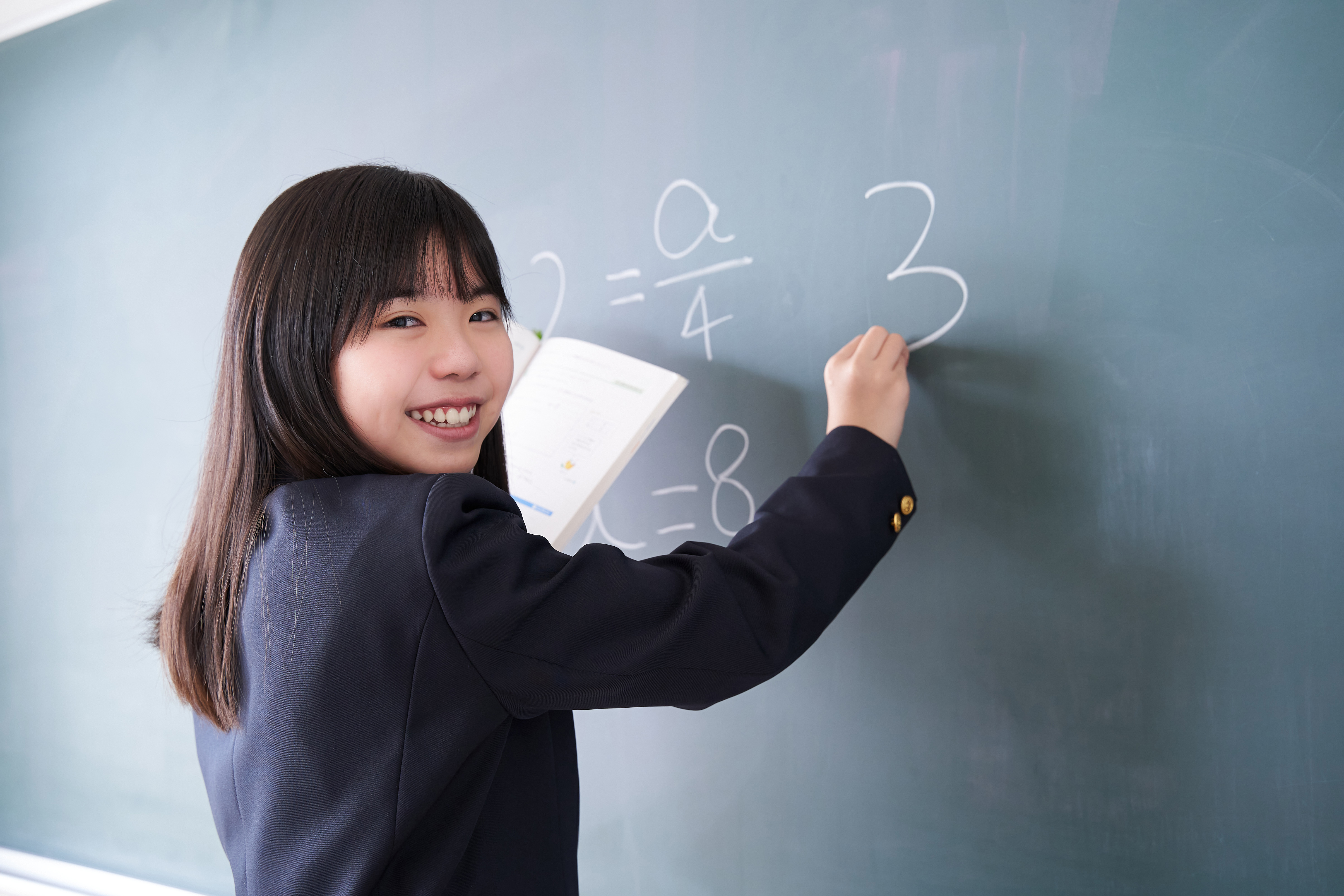 Student solving equations on a chalkboard during a math olympiad training session.