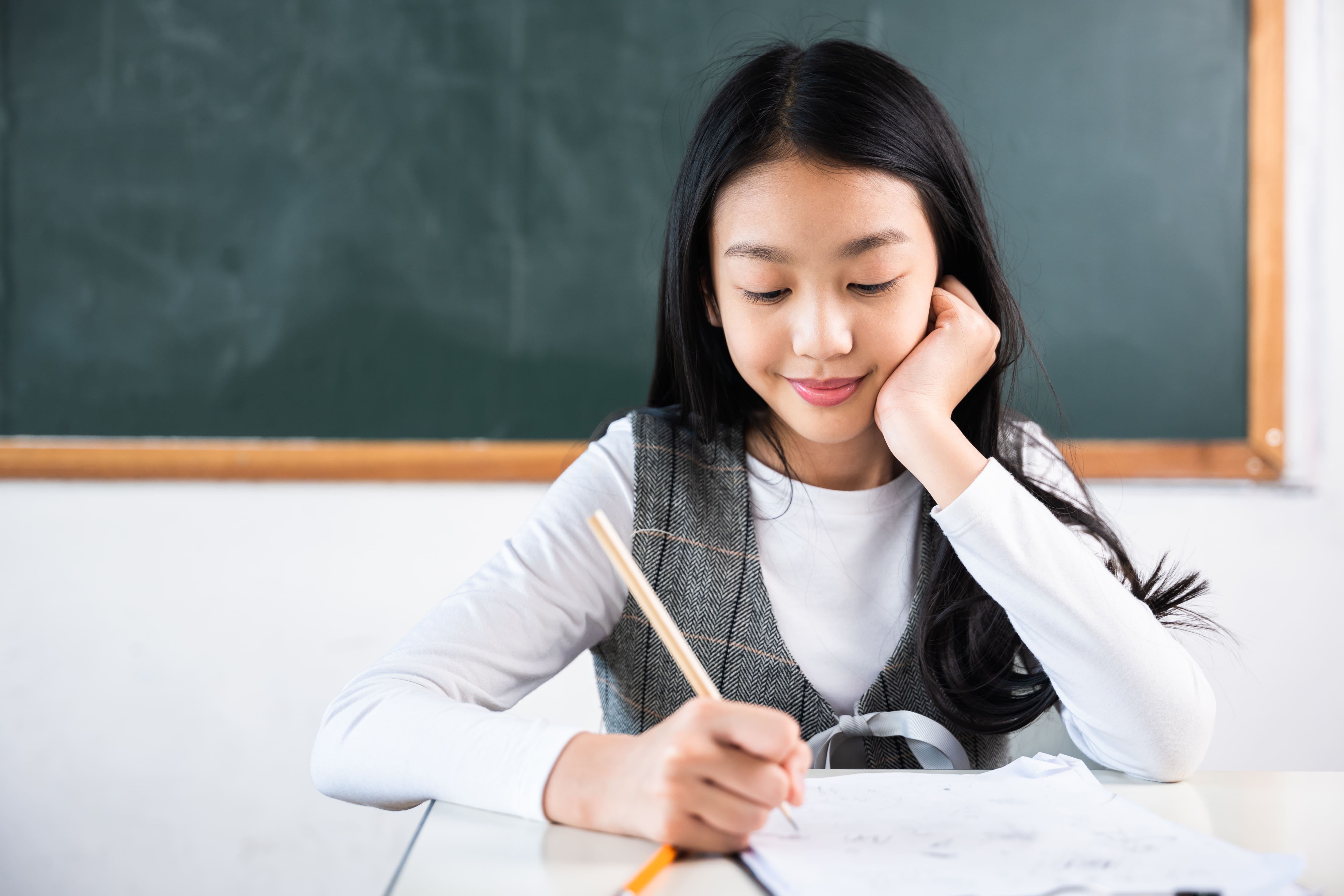 Student solving math problems in a classroom while preparing for a math olympiad competition.