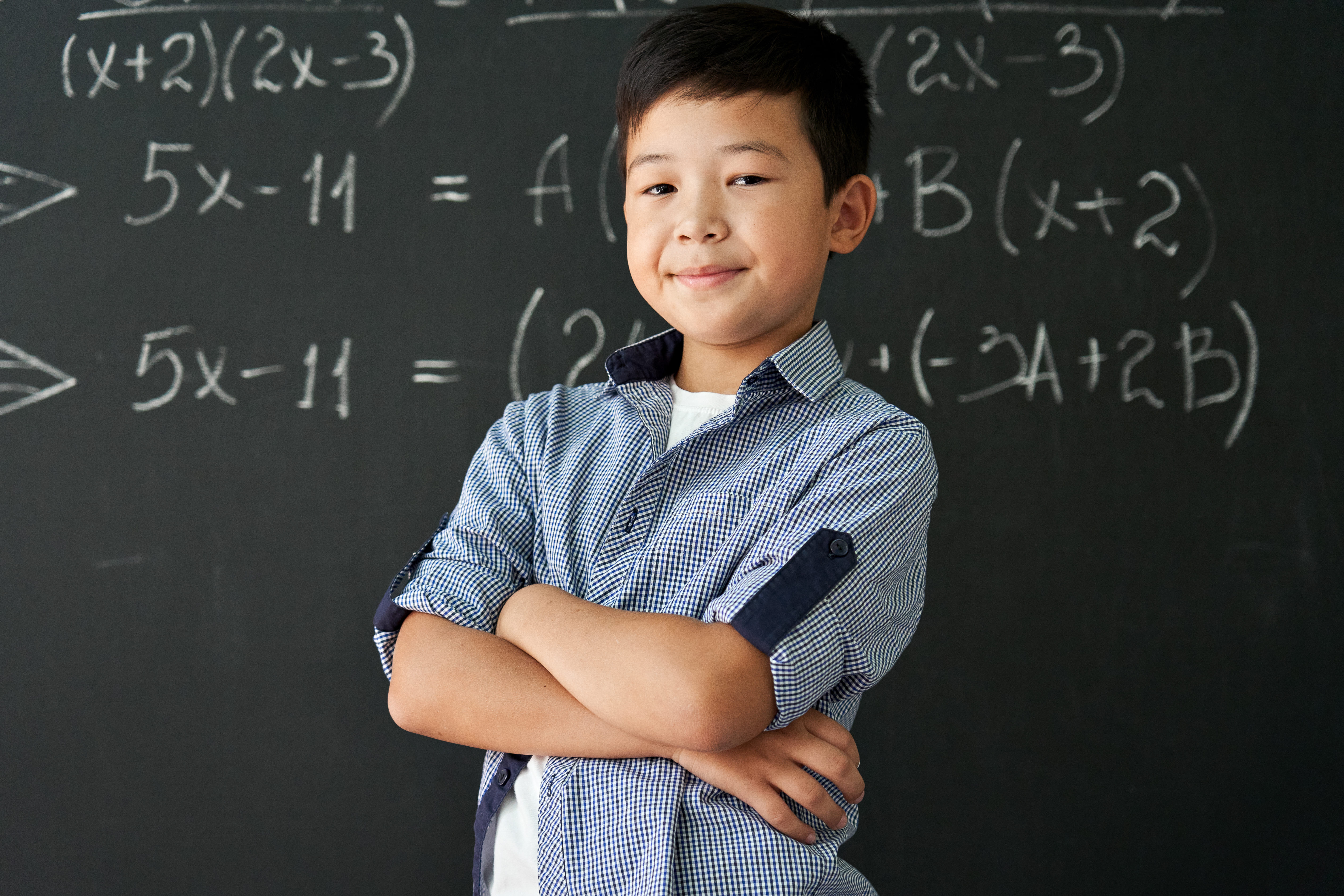 a young math olympiad smiling confidently, with a blackboard at the back with math equations