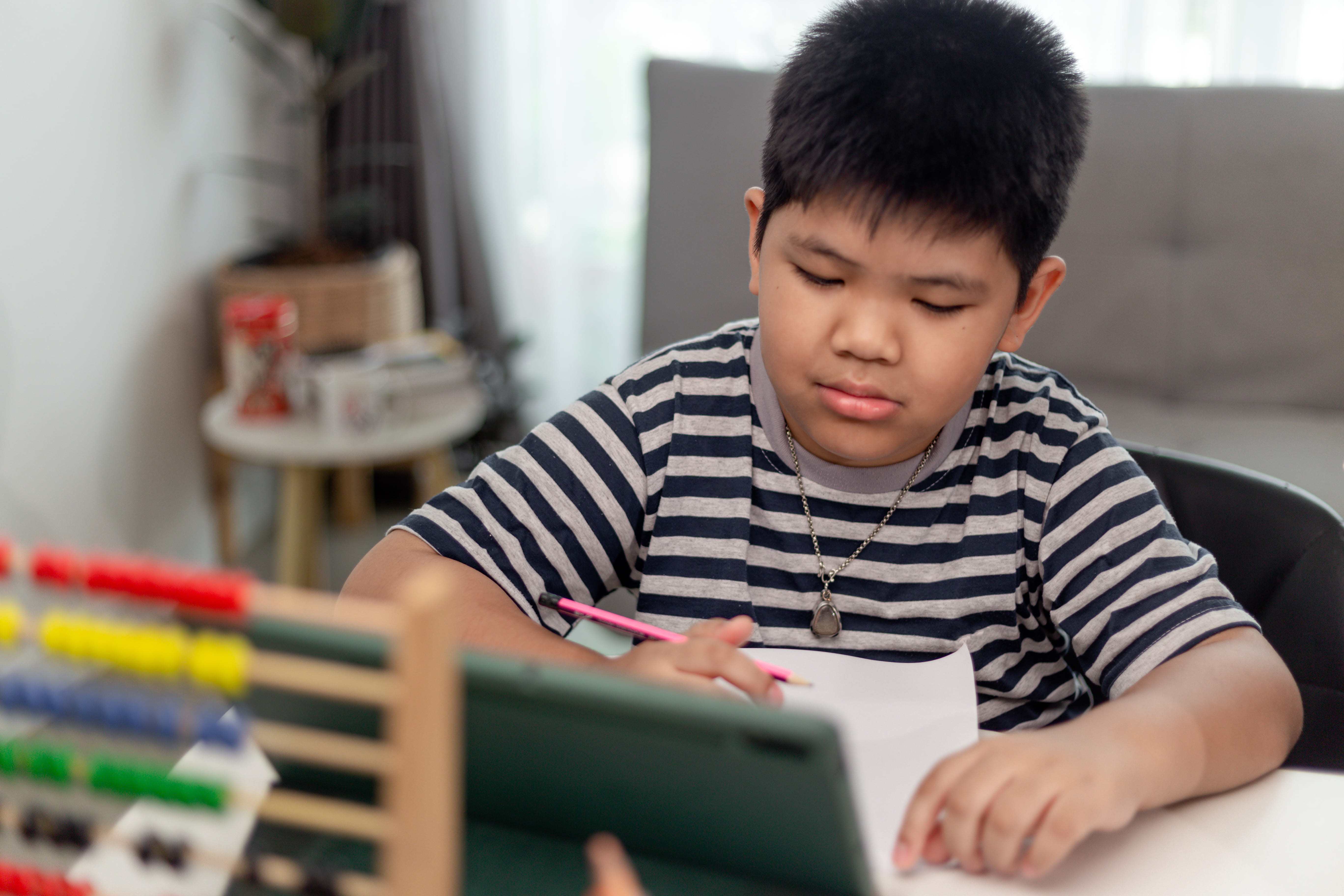 Primary school student using an abacus while working through Maths practice questions.
